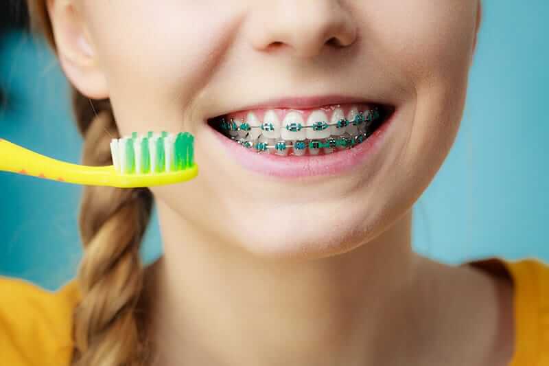 young girl brushing teeth with braces